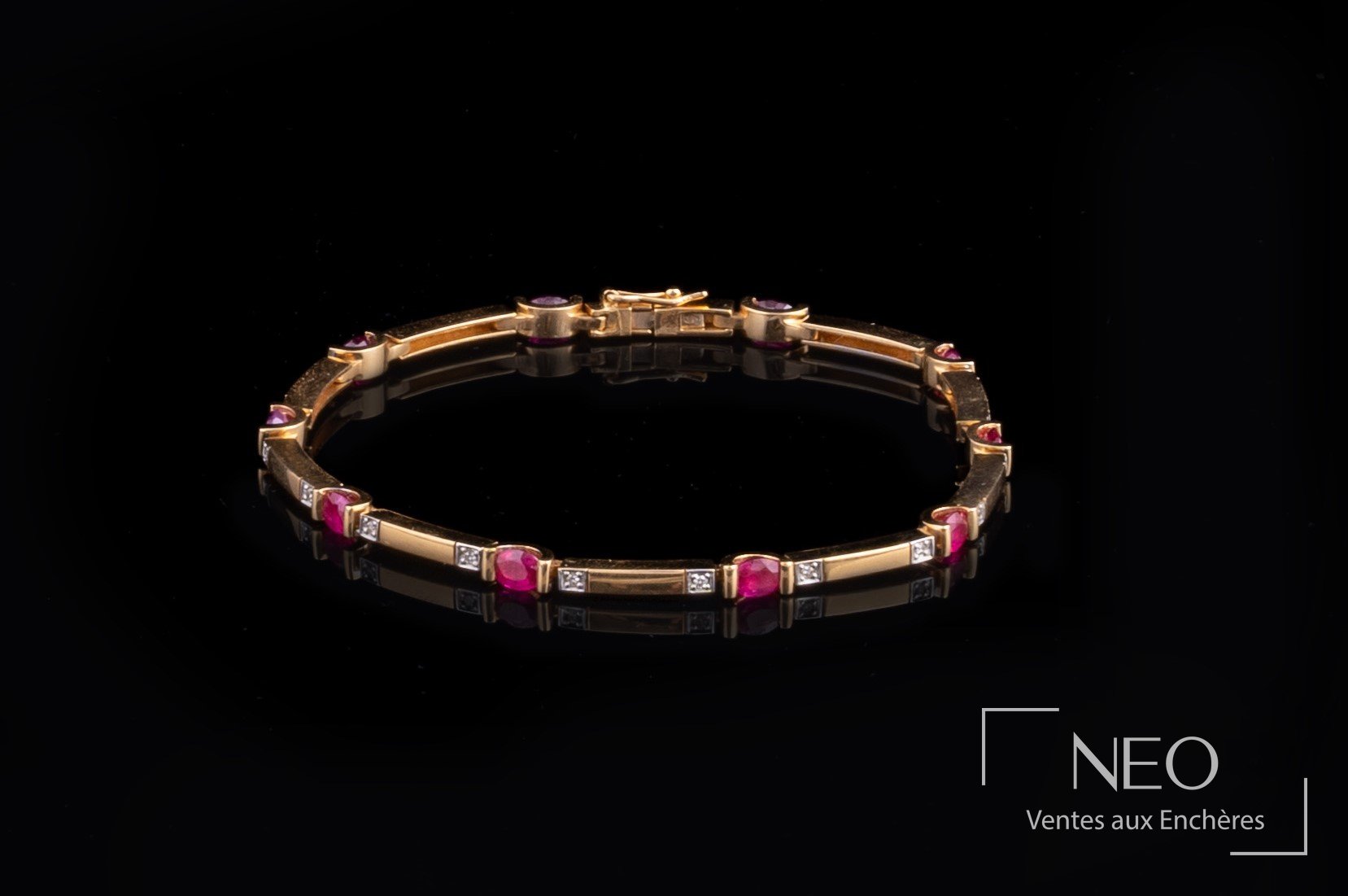 Bracelet ligne en or jaune avec pierres rouges et petits éclats de diamants sur fond noir