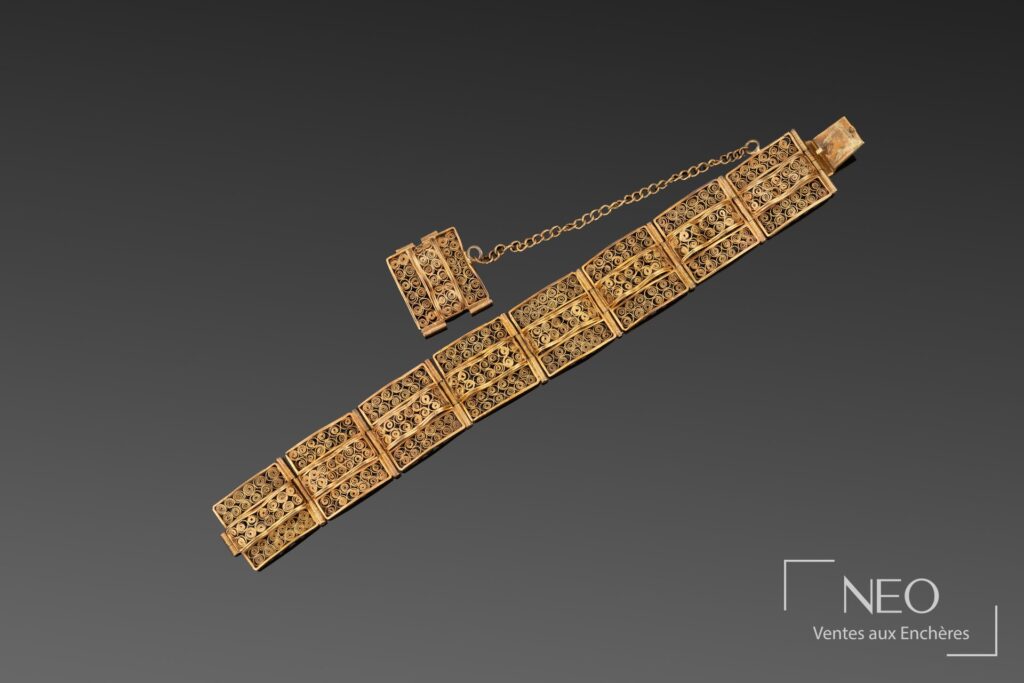 Bracelet en or jaune à plaques carrées et filigrane sur fond gris