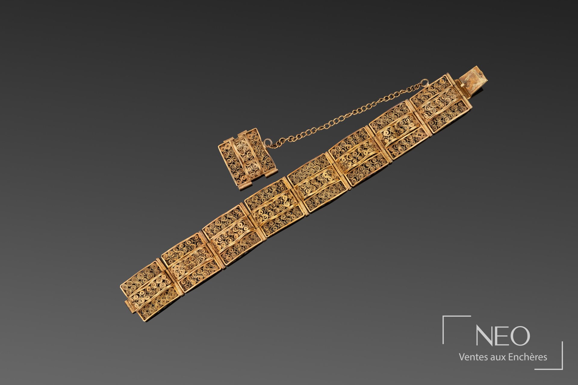 Bracelet en or jaune à plaques carrées et filigrane sur fond gris