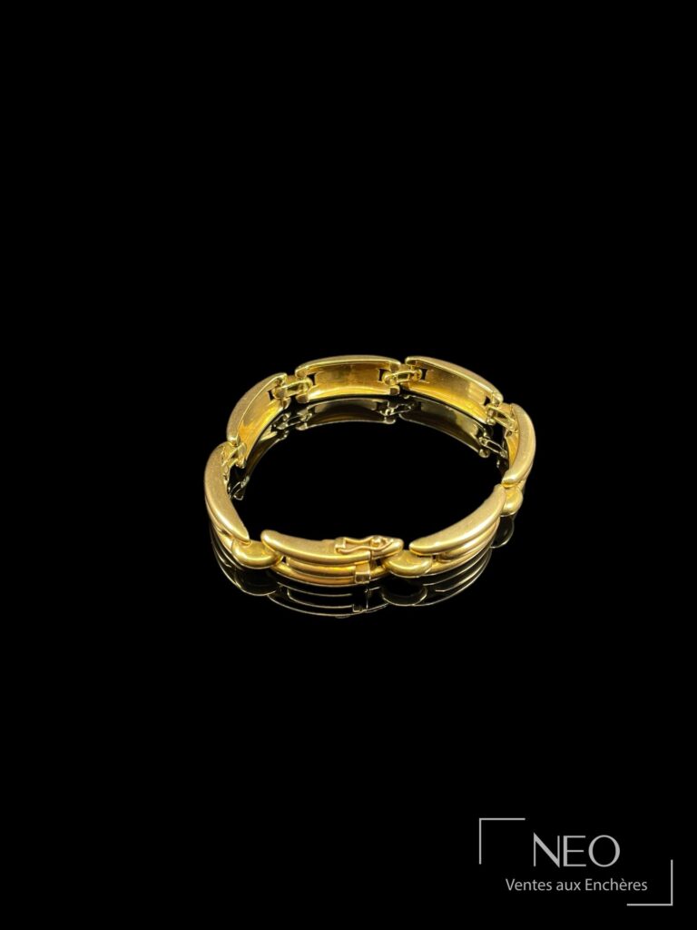 Bracelet en or jaune articulé vu de face sur fond noir