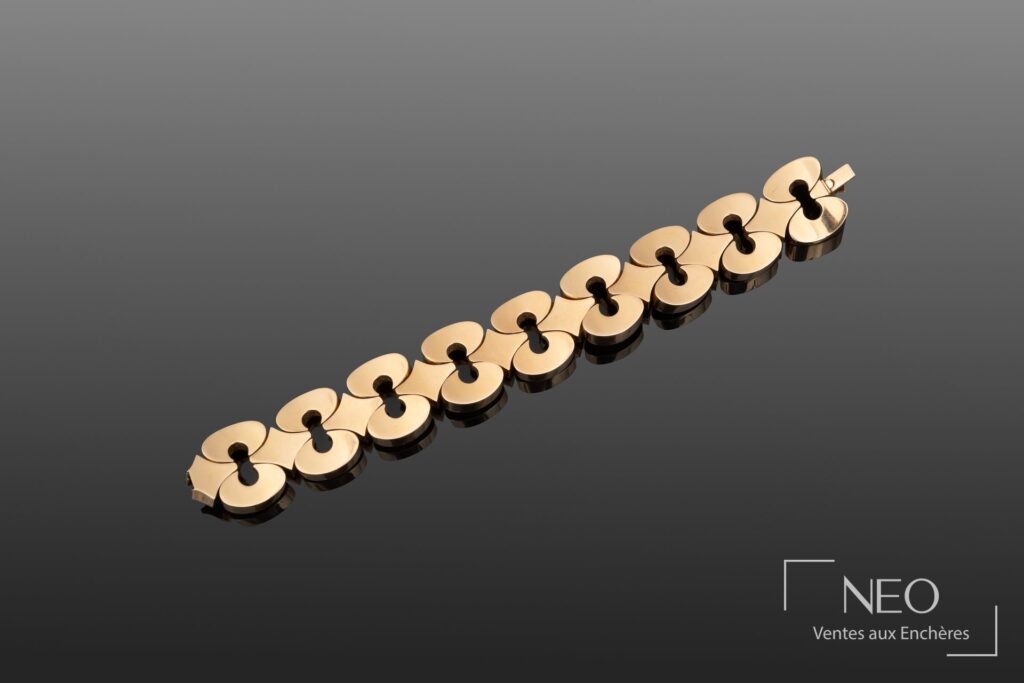 Bracelet en or jaune à neuf maillons ajourés sur fond gris