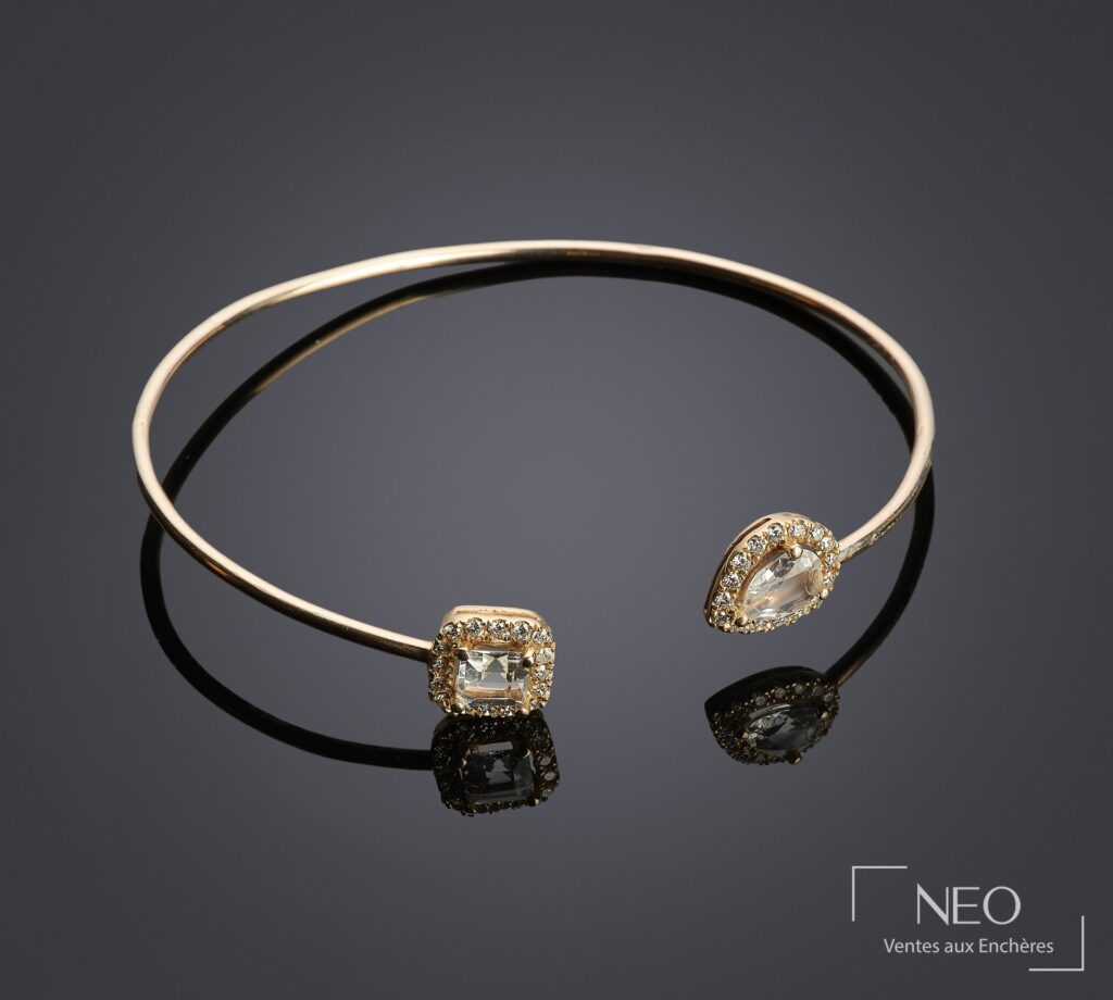 Bracelet jonc en or jaune orné de deux topazes blanches entourées de petits diamants