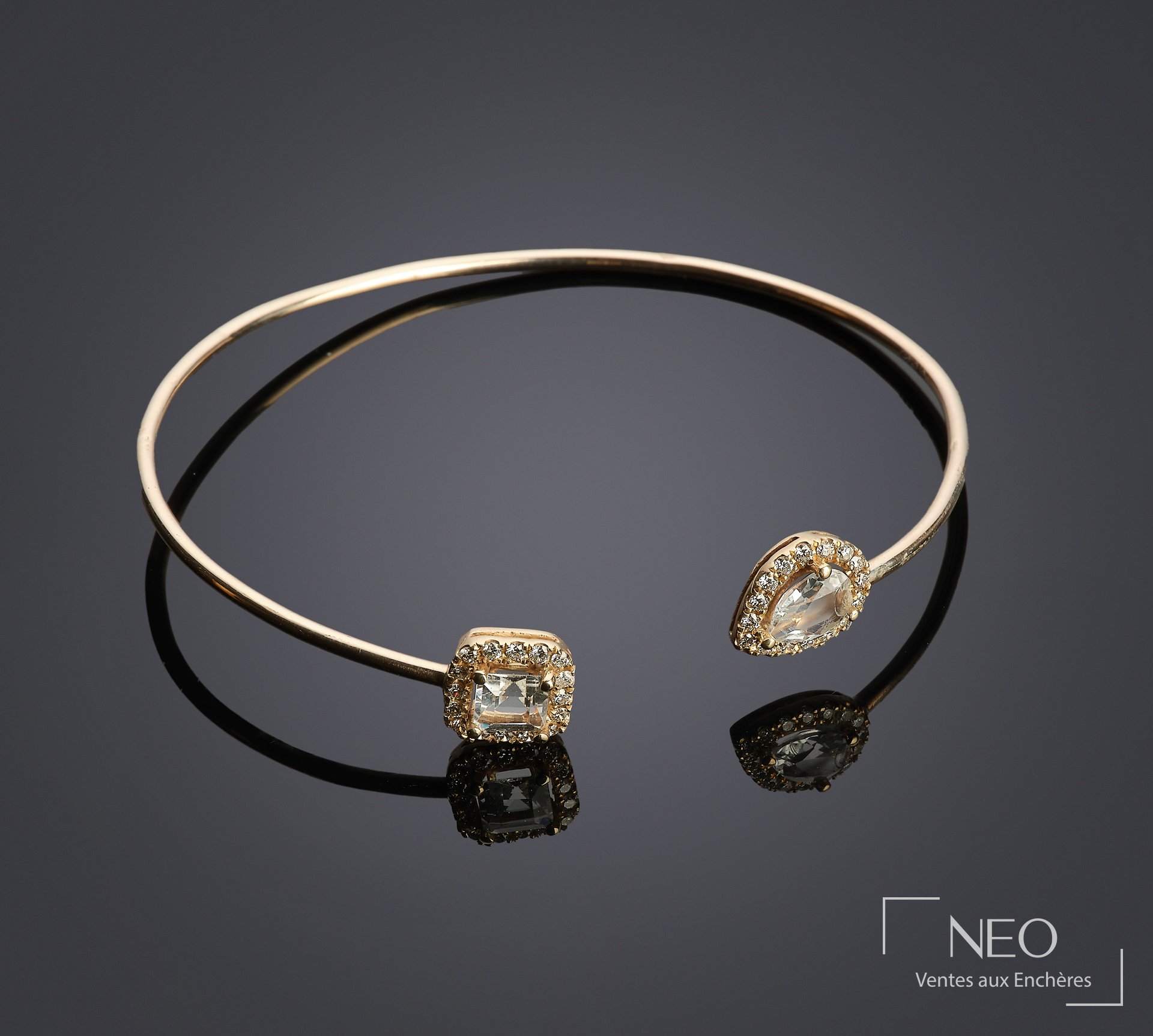 Bracelet jonc en or jaune orné de deux topazes blanches entourées de petits diamants