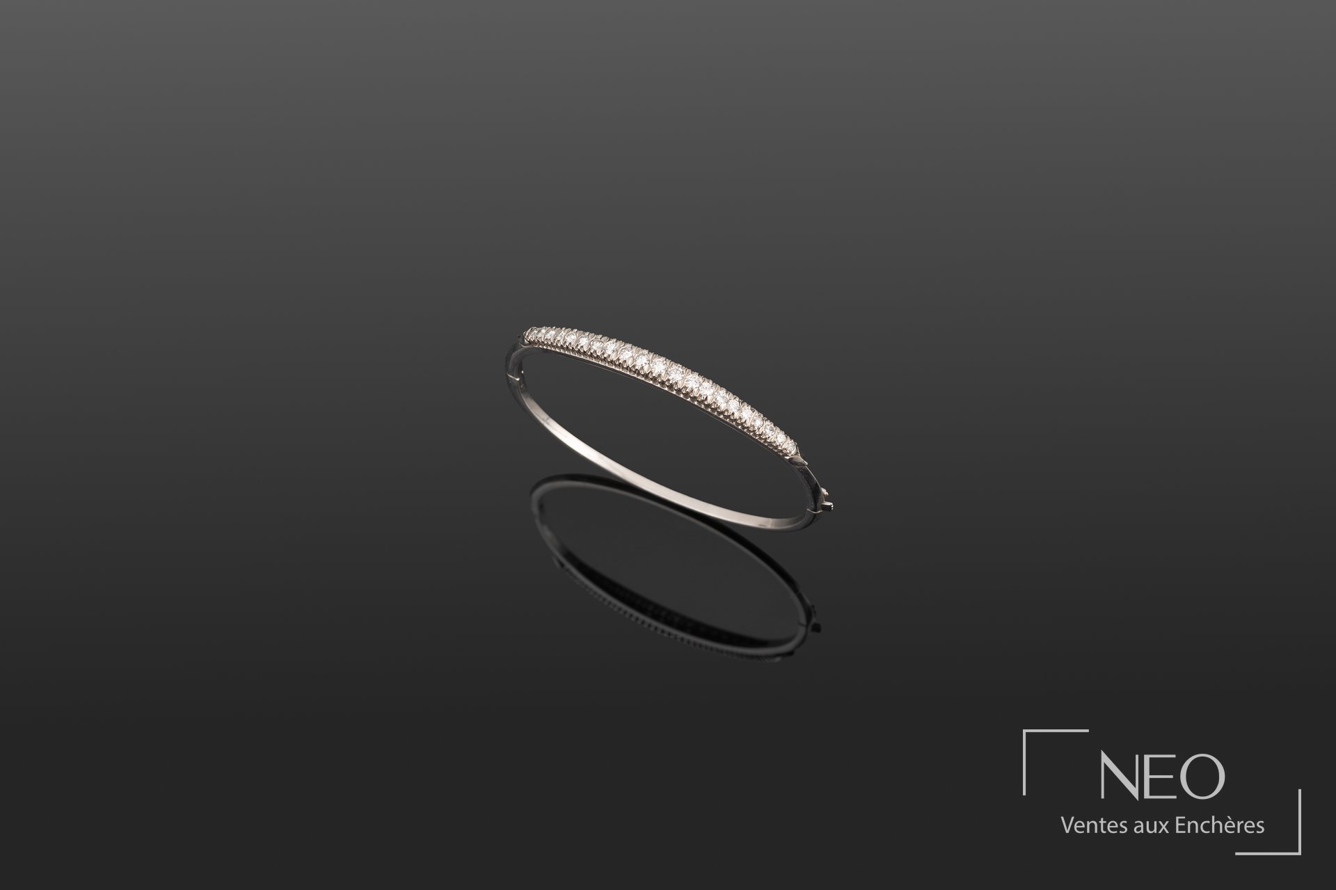 Bracelet rigide ouvrant en or blanc serti d'une ligne de diamants sur fond sombre