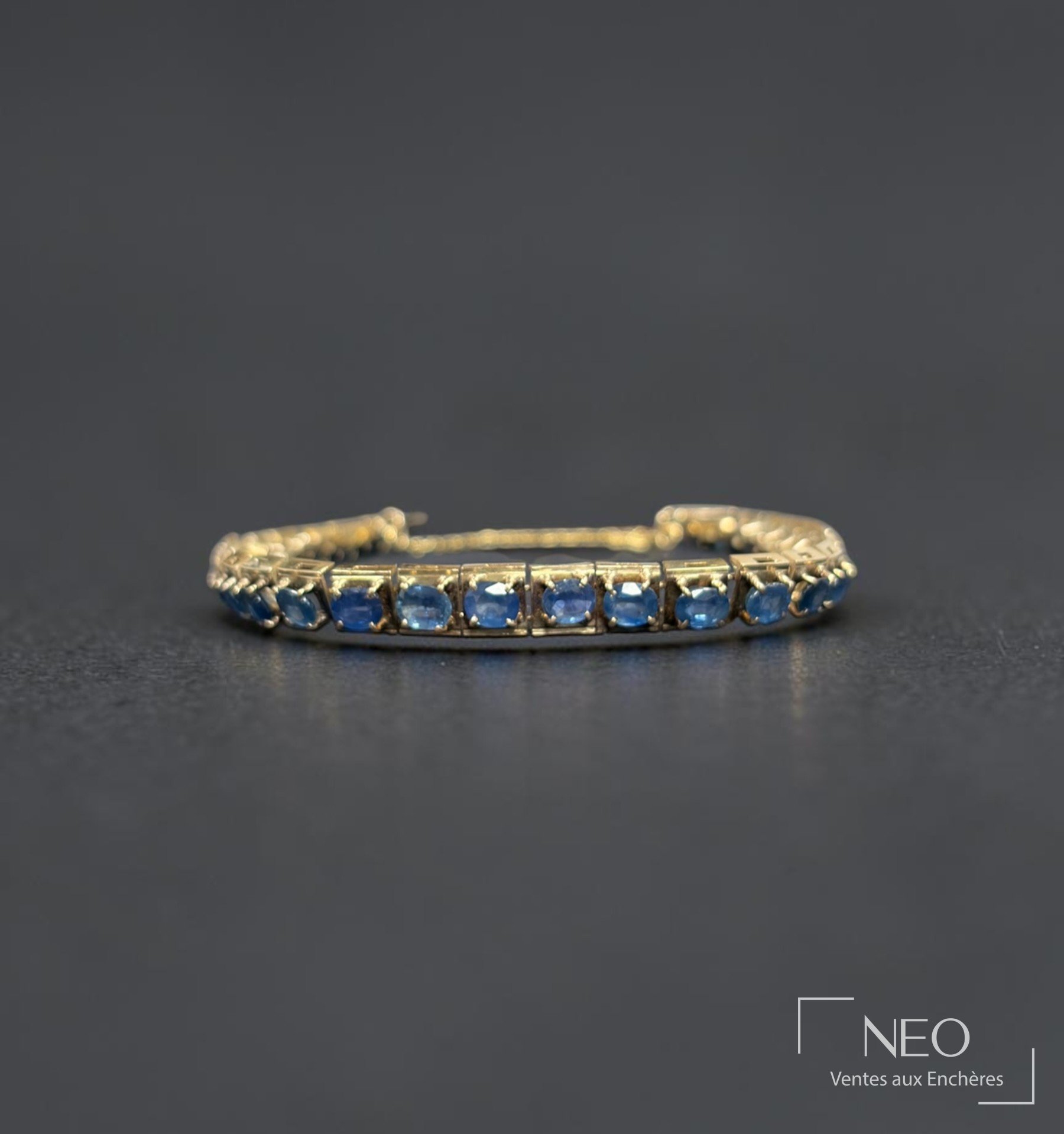 Bracelet articulé en or jaune serti de saphirs bleus sur fond sombre