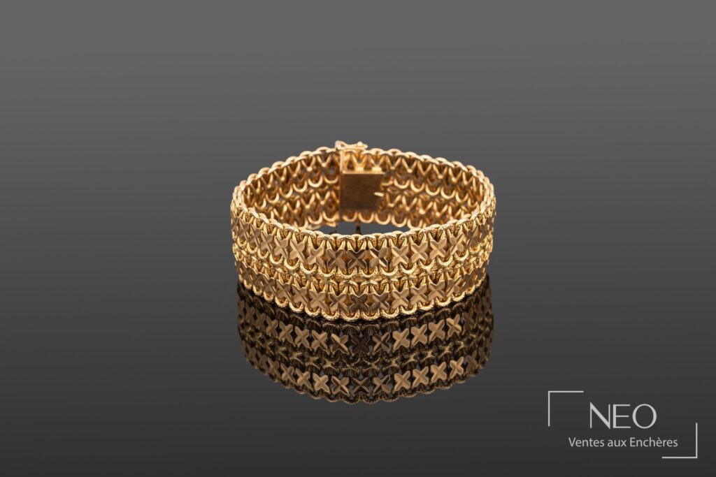Bracelet souple en or jaune à maille croisillon fantaisie sur fond gris