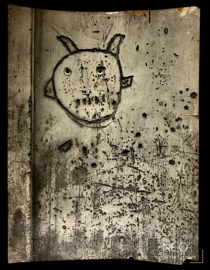 Photographie de Brassaï montrant un graffiti avec visage stylisé sur fond de mur