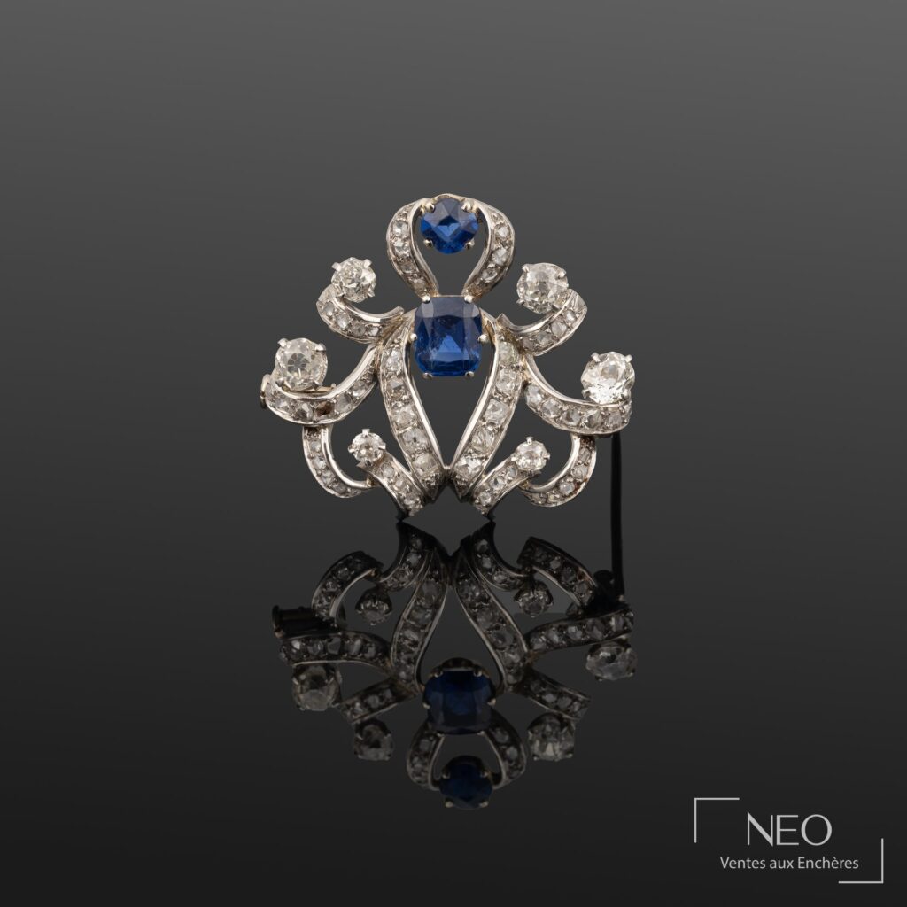 Broche ancienne en platine sertie de deux saphirs bleus et de diamants sur fond sombre