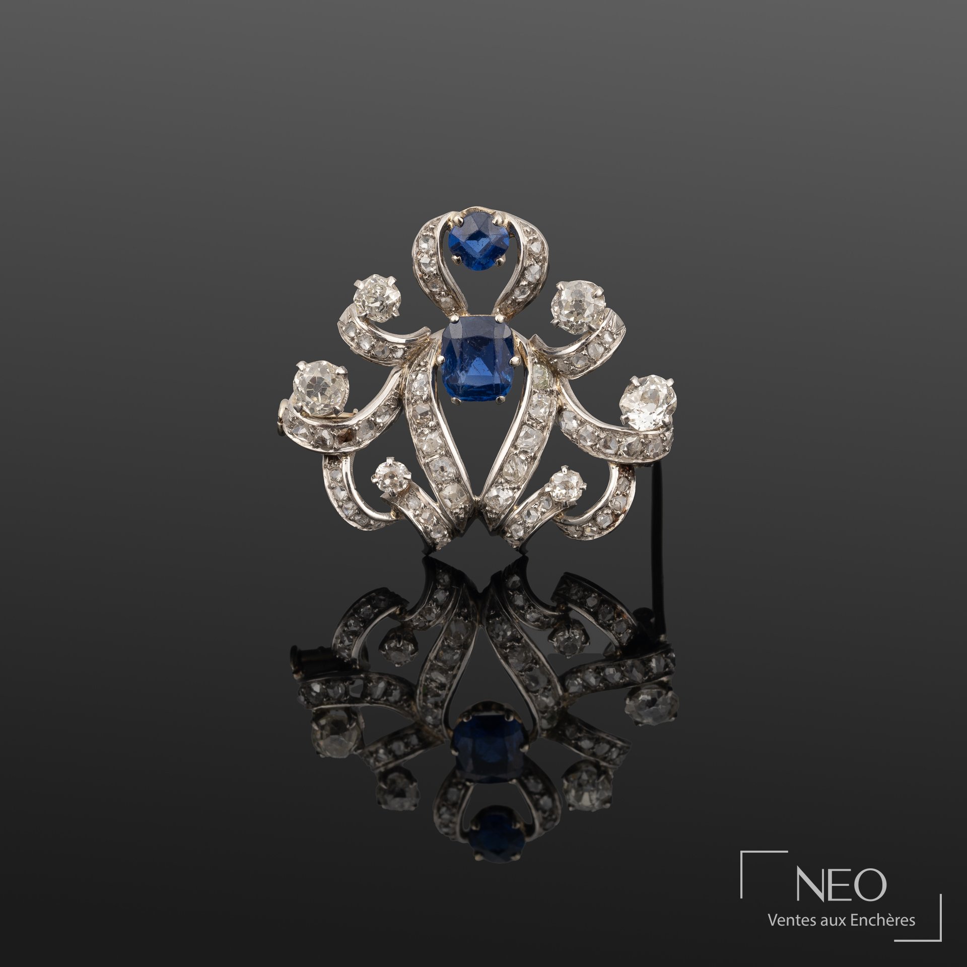 Broche ancienne en platine sertie de deux saphirs bleus et de diamants sur fond sombre