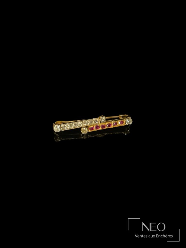 Broche barrette en or jaune avec deux rangs sertis de diamants et de pierres rouges sur fond noir