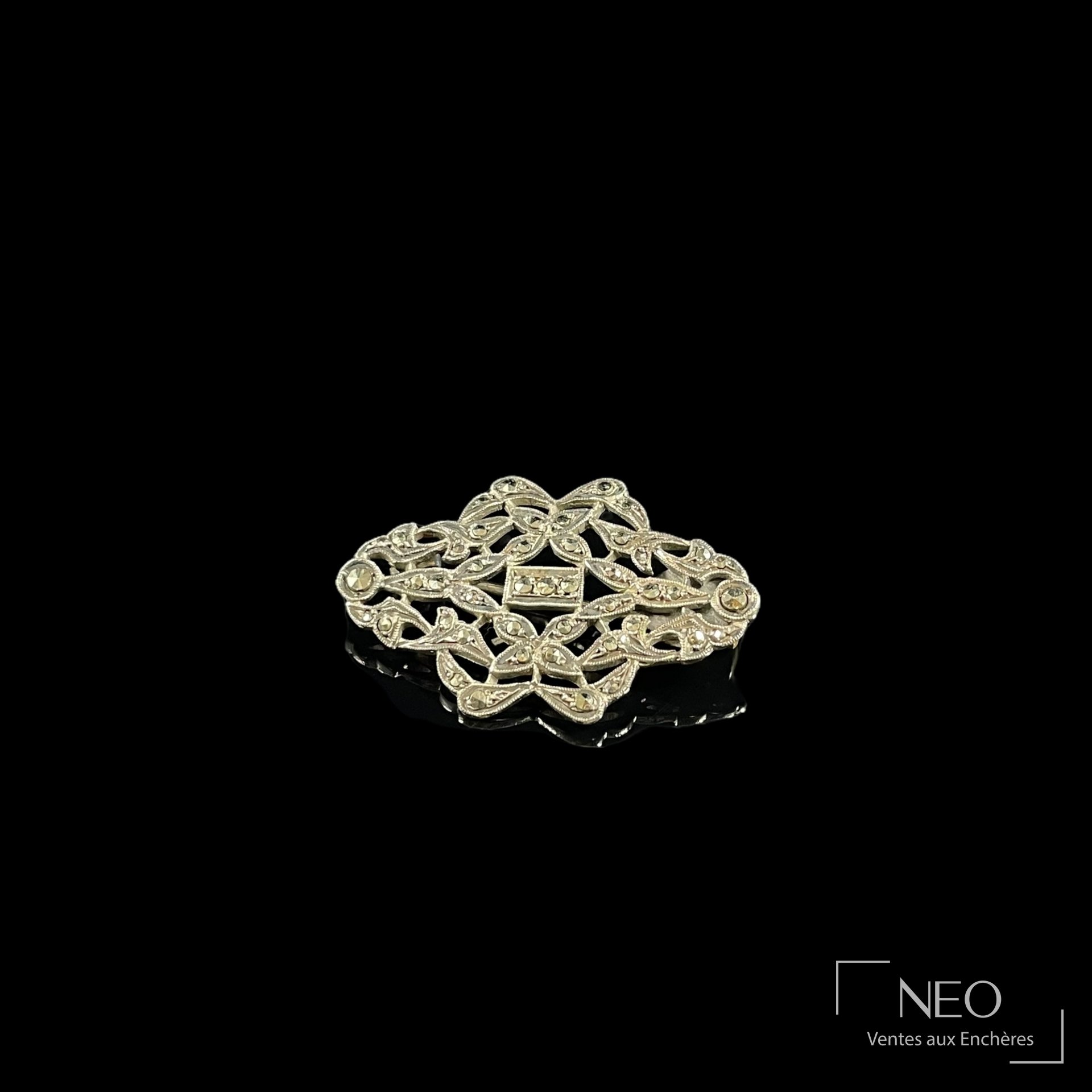 Broche en argent ajouré ornée de petites pierres noires sur fond noir