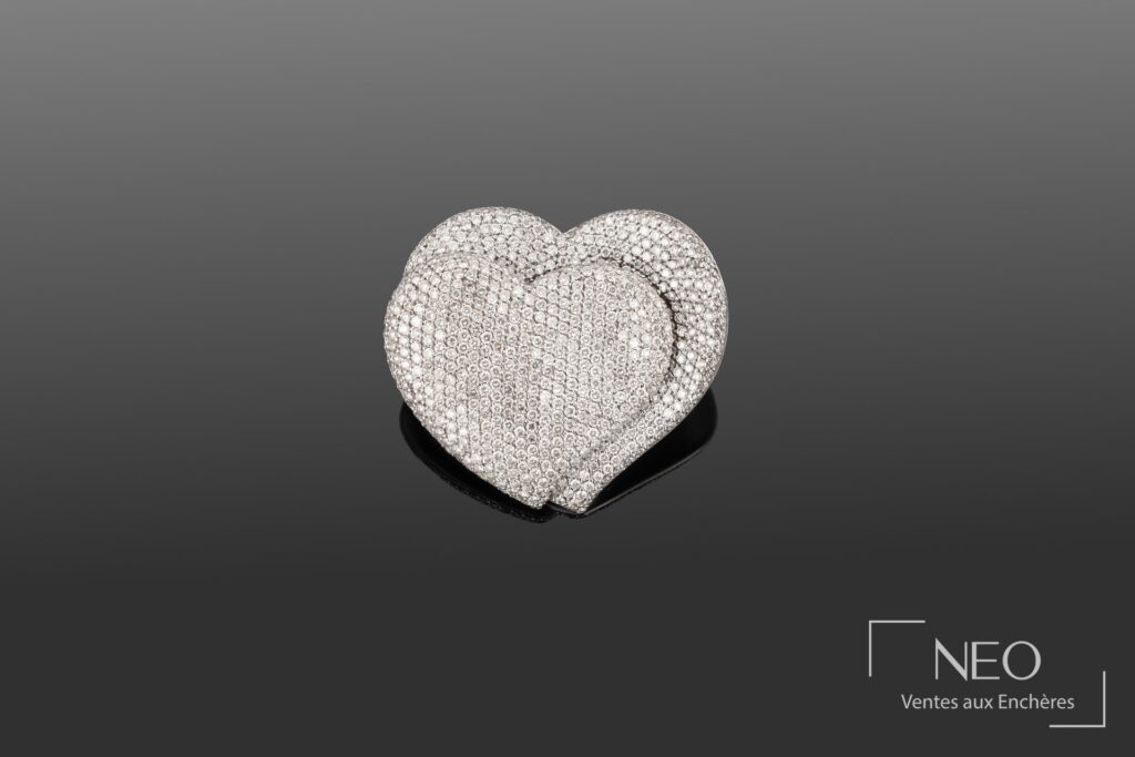 Broche en forme de deux cœurs pavée de diamants sur fond gris