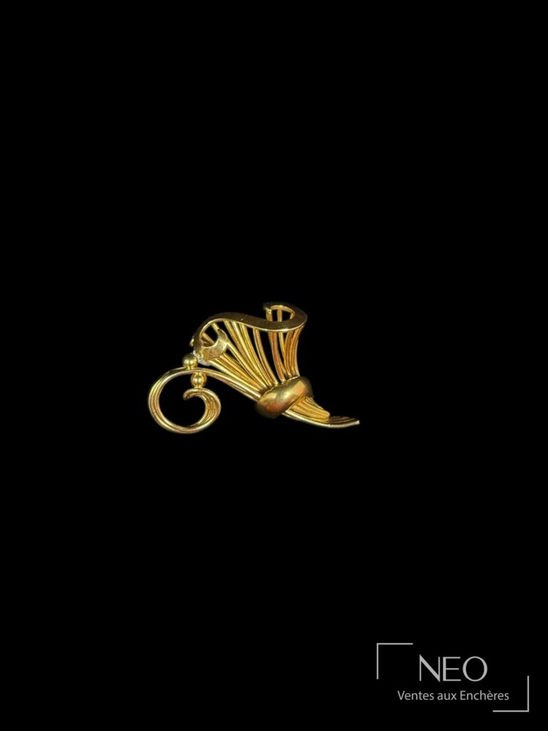 Broche en or jaune ajourée en forme de S sur fond noir