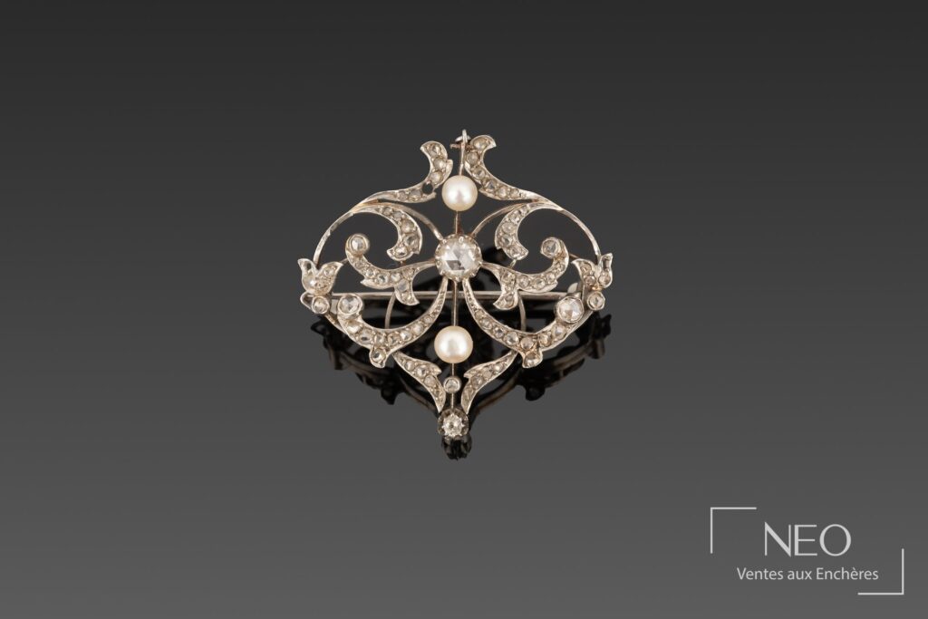 Broche ajourée en platine avec diamants et deux perles blanches sur fond gris
