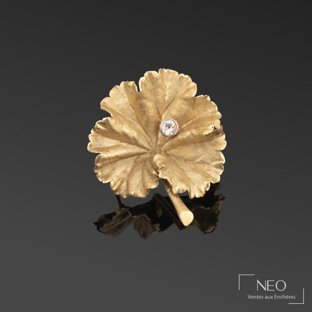 Broche feuille en or jaune avec diamant central sur fond sombre