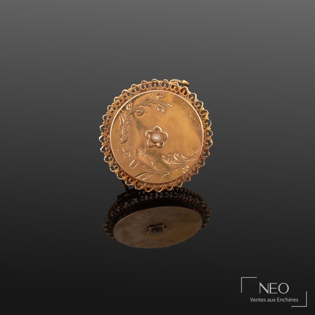 Broche ronde en or jaune avec décor ajouré et perle blanche centrale