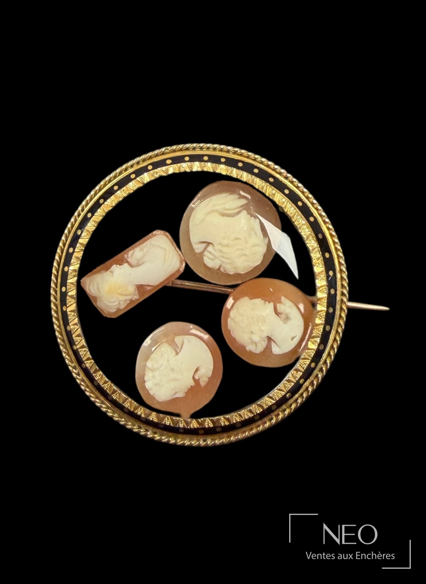 Broche ronde en or jaune et émail noir avec quatre camées coquilles visibles à l'avant.