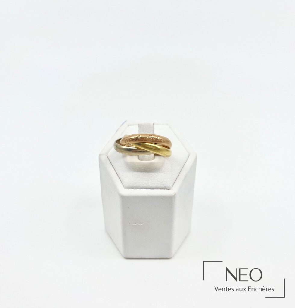 Bague Cartier Trinity en trois ors posée sur un support blanc