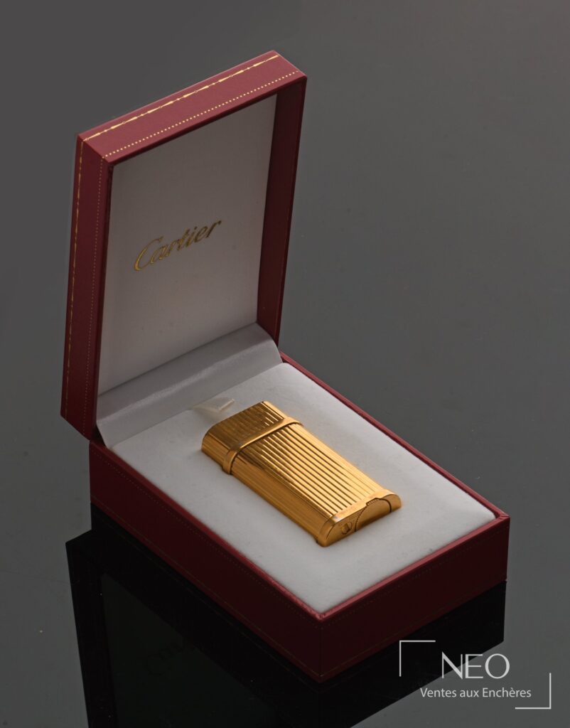 Briquet Cartier Must en métal plaqué or dans son écrin rouge ouvert