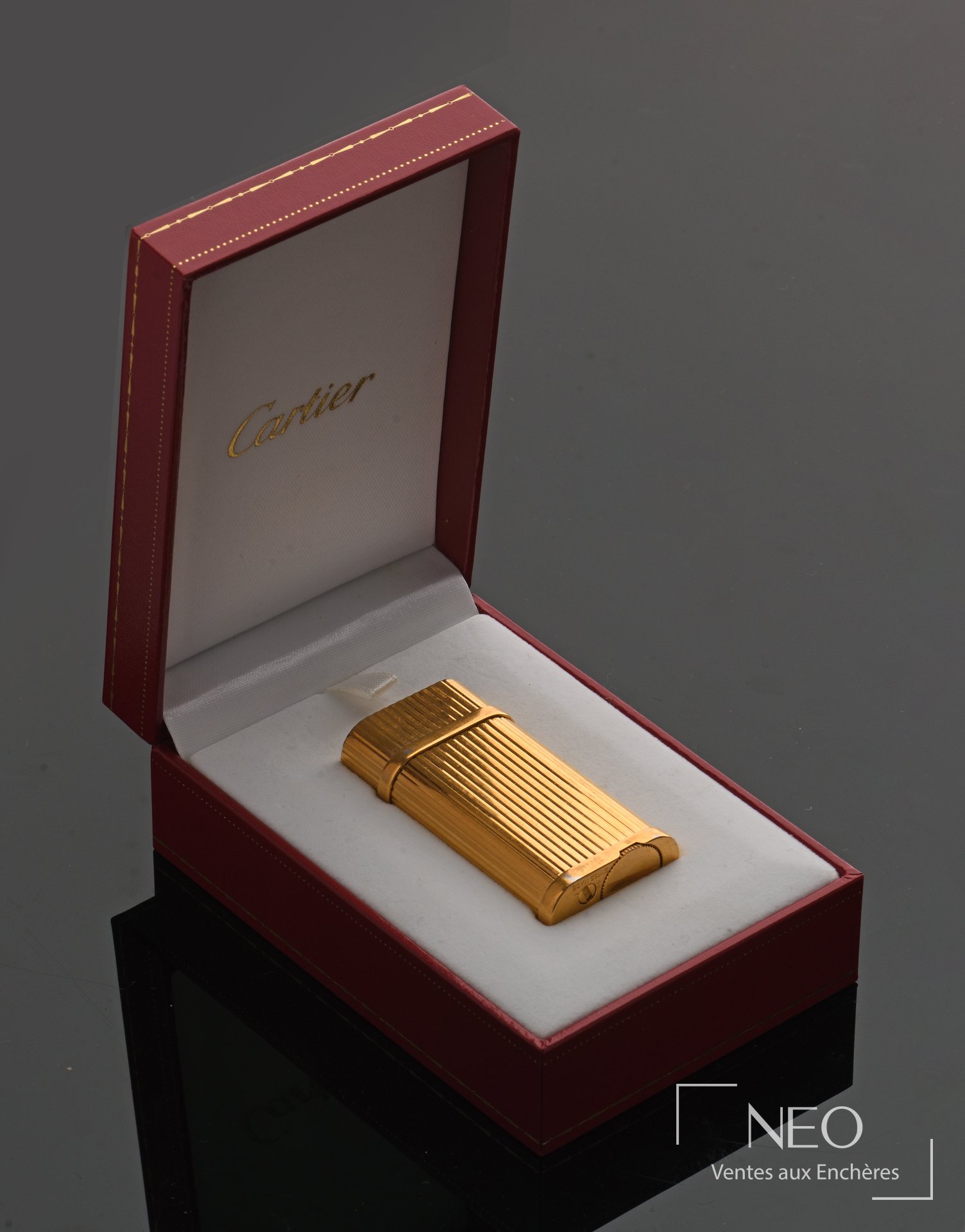 Briquet Cartier Must en métal plaqué or dans son écrin rouge ouvert