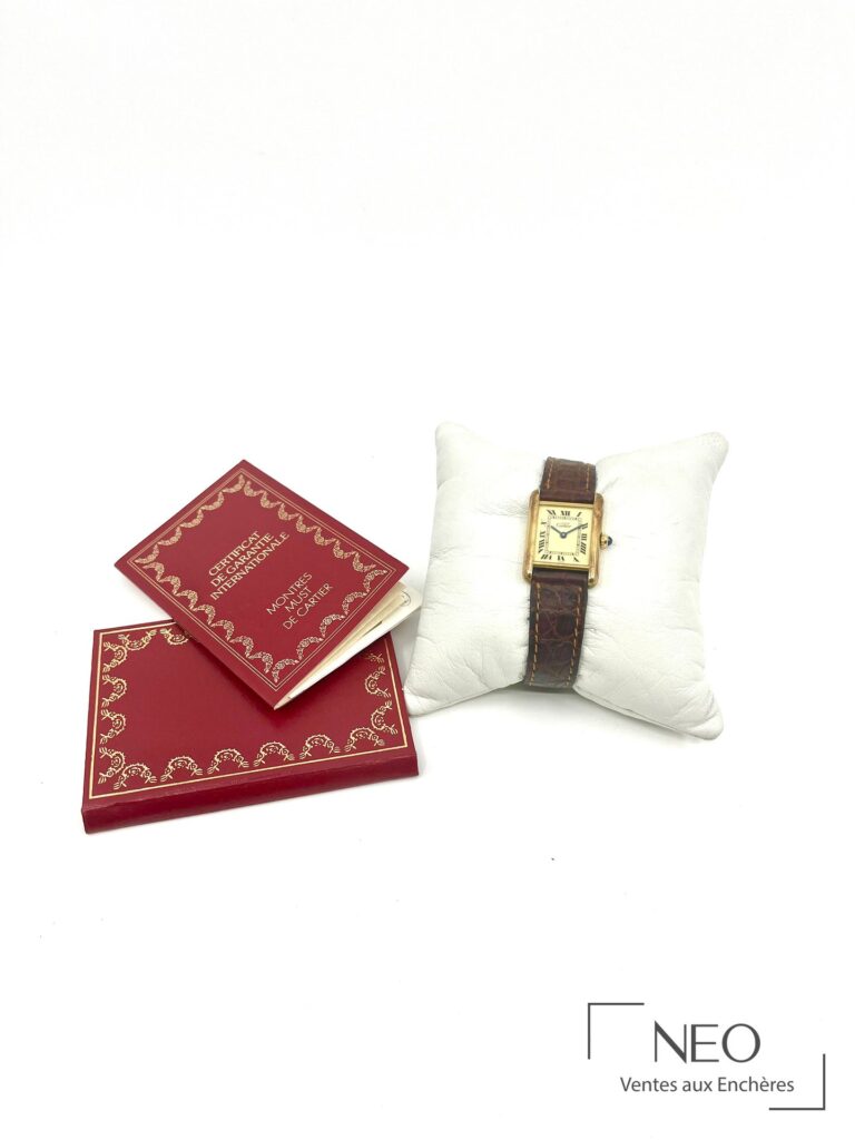 Montre Cartier Tank avec son coffret rouge et son certificat de garantie internationale sur fond blanc