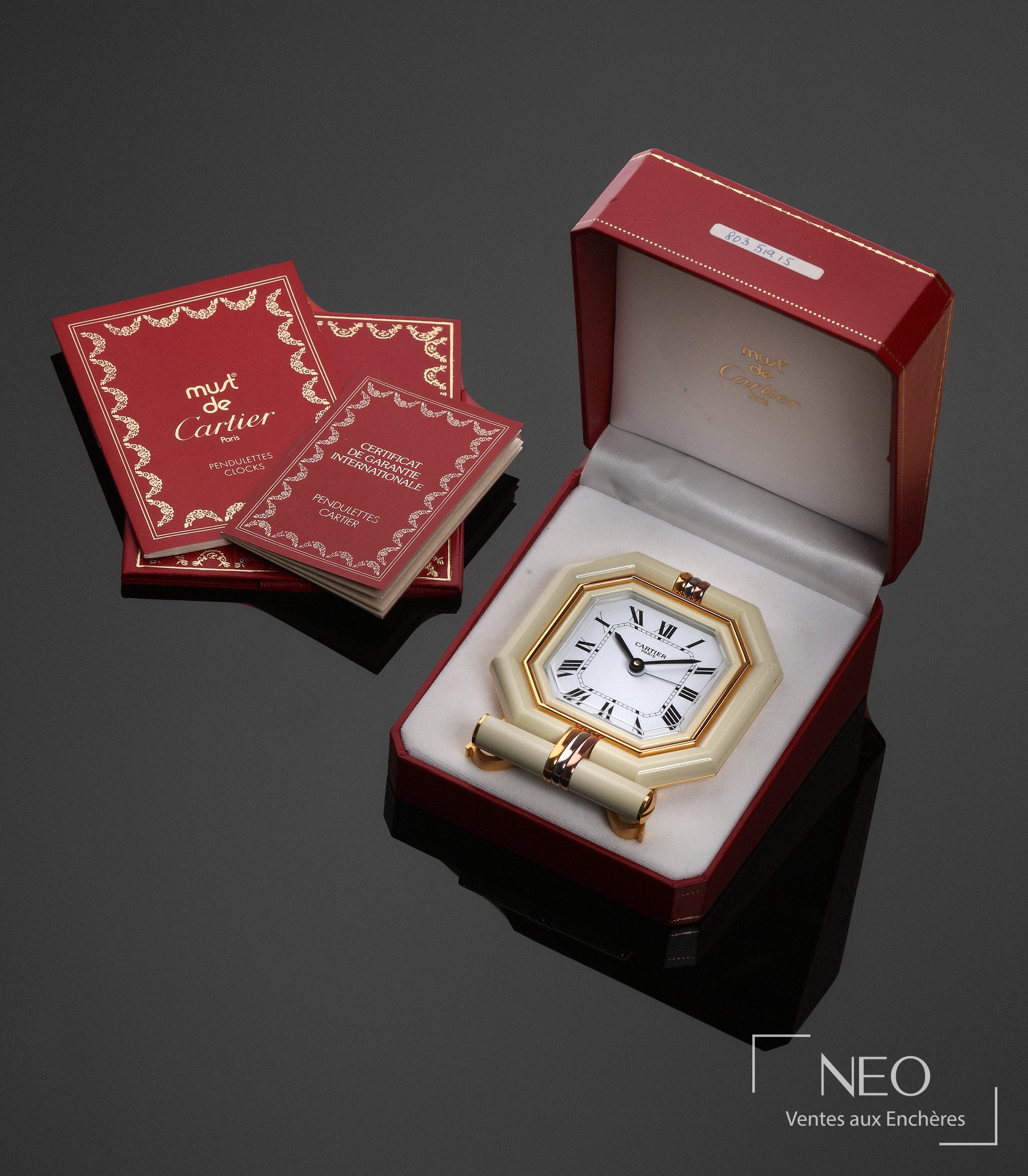 Réveil de voyage Cartier Must présenté ouvert dans son écrin avec ses papiers