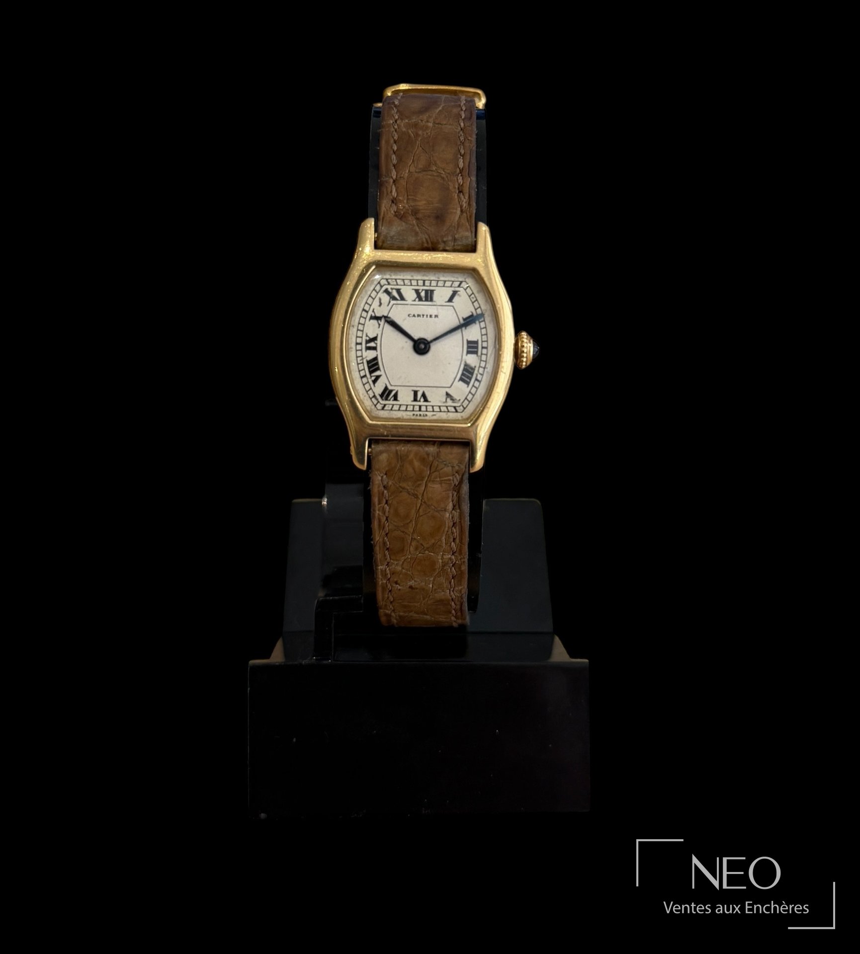 Montre Cartier Tortue en or jaune avec cadran crème à chiffres romains et bracelet cuir.