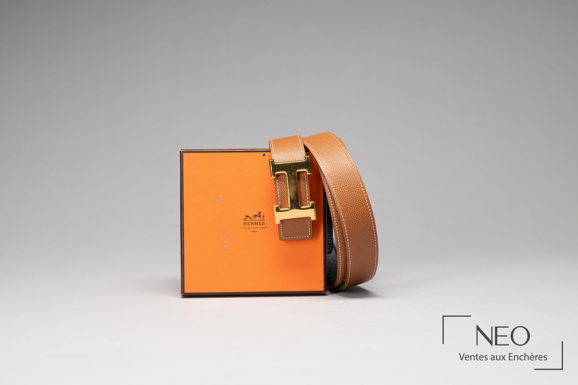 Ceinture Hermès réversible posée contre sa boîte orange