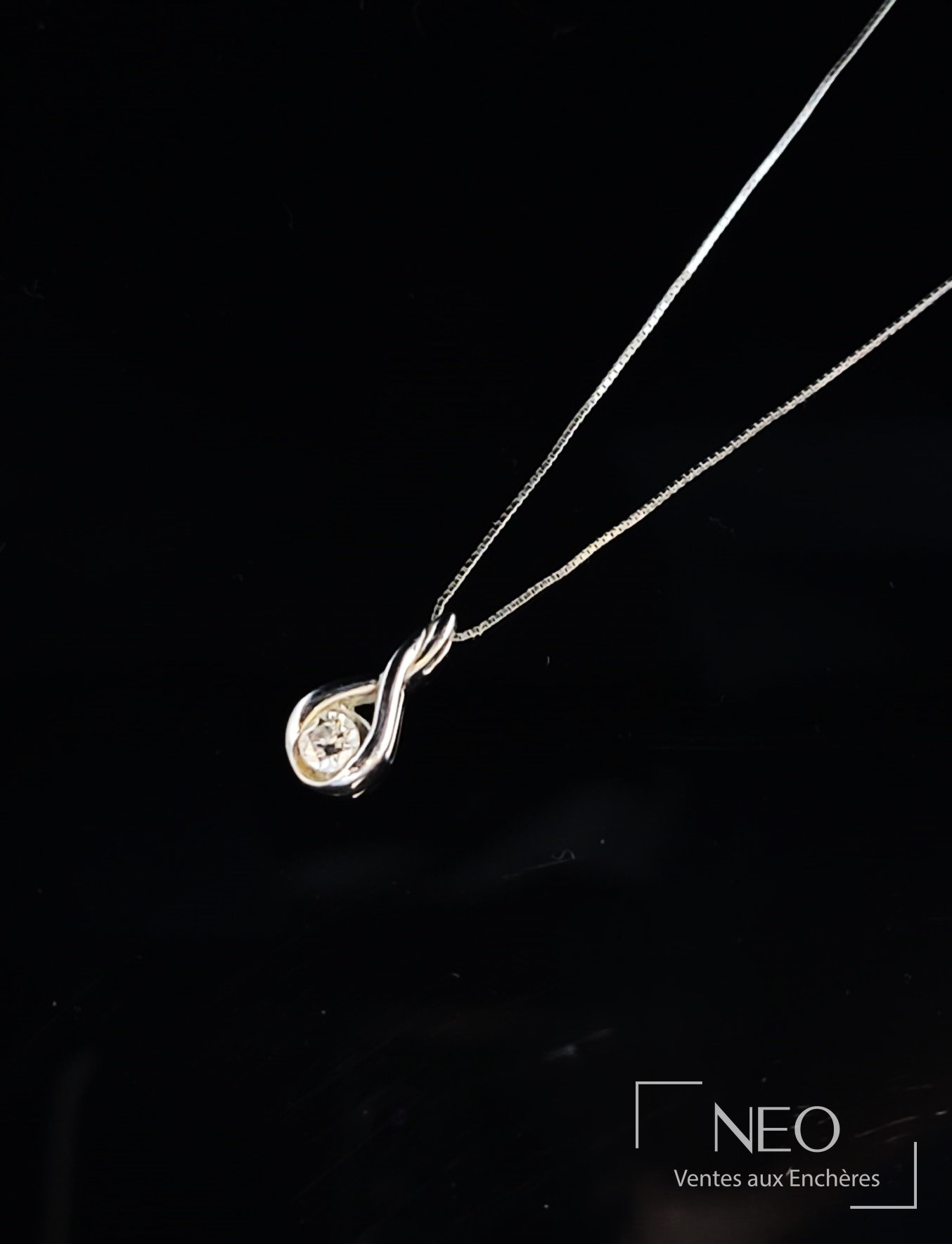 Chaîne de cou en or gris avec pendentif serti d’un diamant sur fond noir