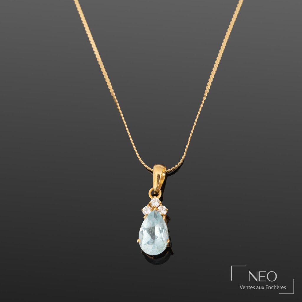 Chaîne de cou en or jaune avec pendentif à pierre bleue facettée et trois pierres blanches