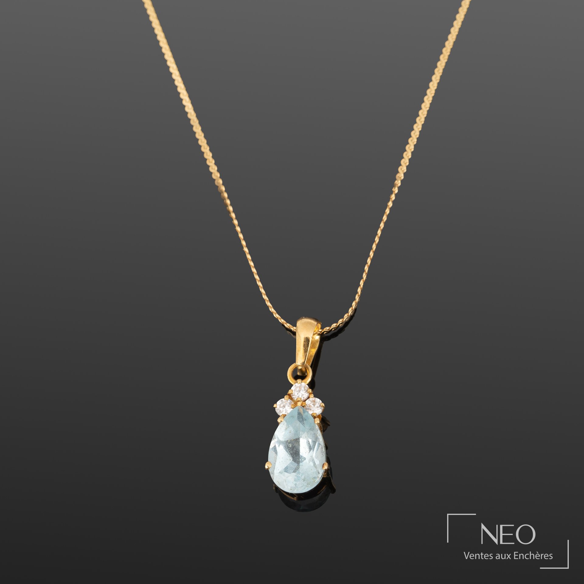 Chaîne de cou en or jaune avec pendentif à pierre bleue facettée et trois pierres blanches