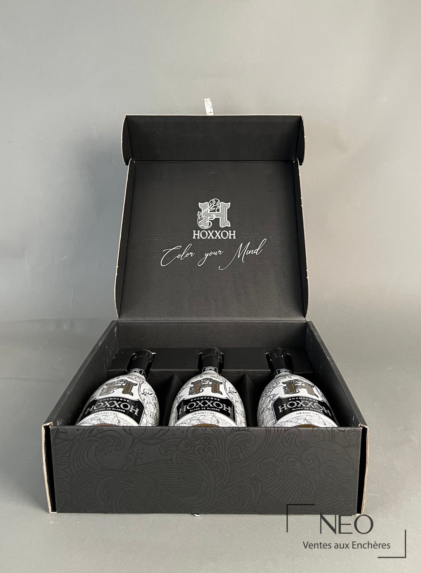 Coffret ouvert avec trois bouteilles de champagne HOXXOH rangées à l'intérieur.