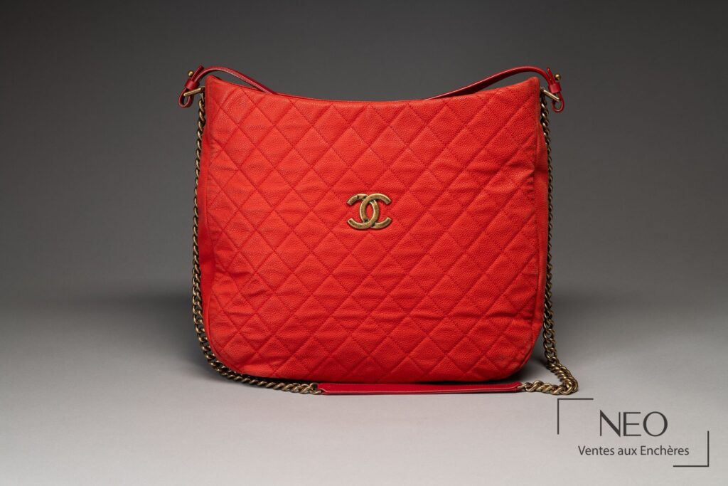 Sac CHANEL rouge corail vu de face avec logo CC doré et bandoulière