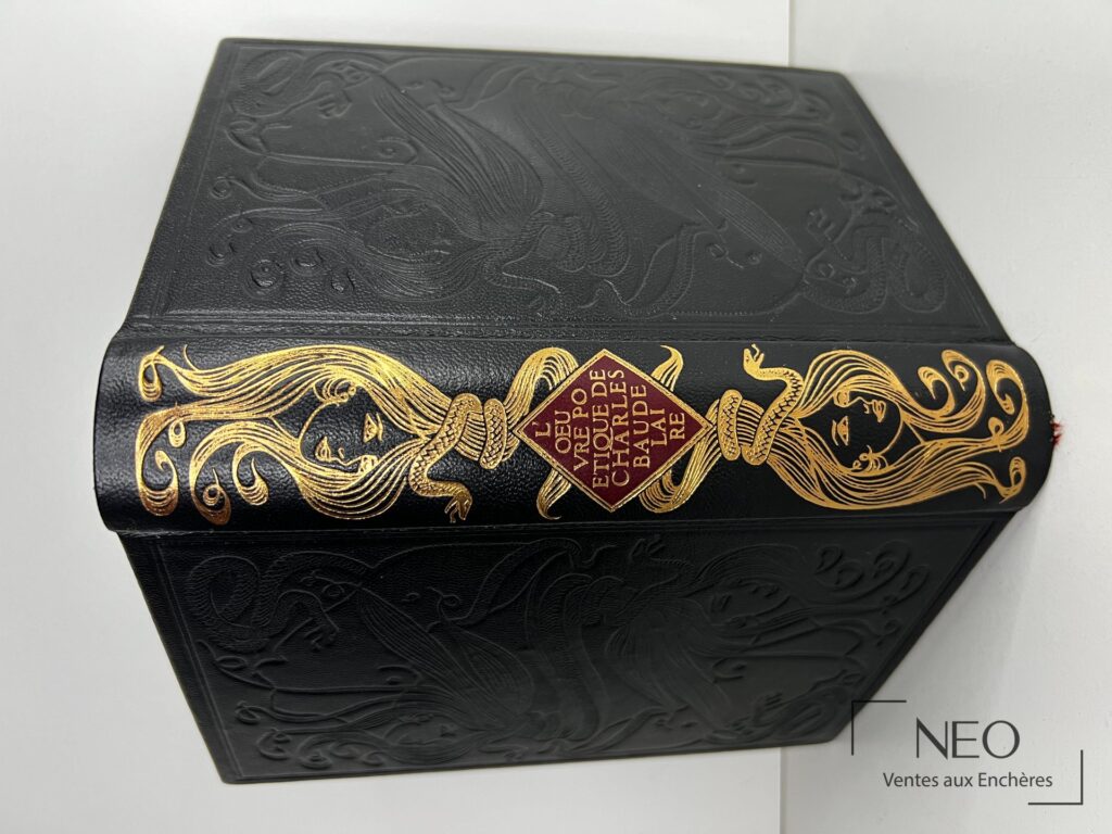 Couverture noire ornée de motifs dorés et décor gaufré sur un livre de Baudelaire