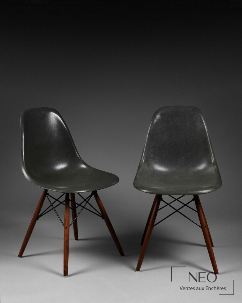 Deux chaises DSW Eames en fibre de verre gris avec piétement en bois.