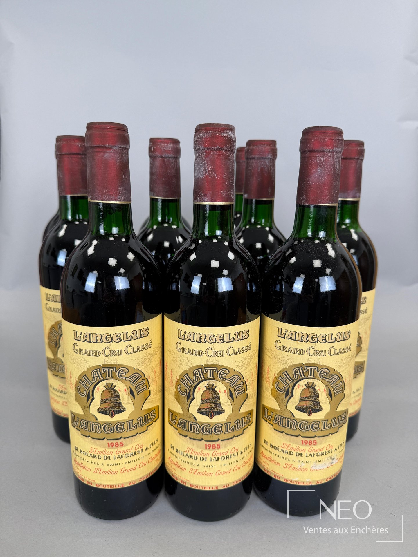 Douze bouteilles de Château L’Angélus 1985 présentées de face avec leurs étiquettes
