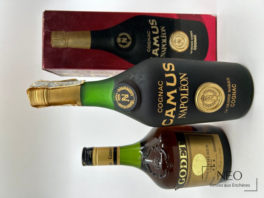Lot de deux bouteilles de cognac avec une boîte Camus visible derrière