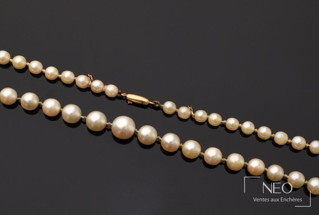 Collier de perles blanches de culture en chute avec fermoir en or jaune sur fond noir