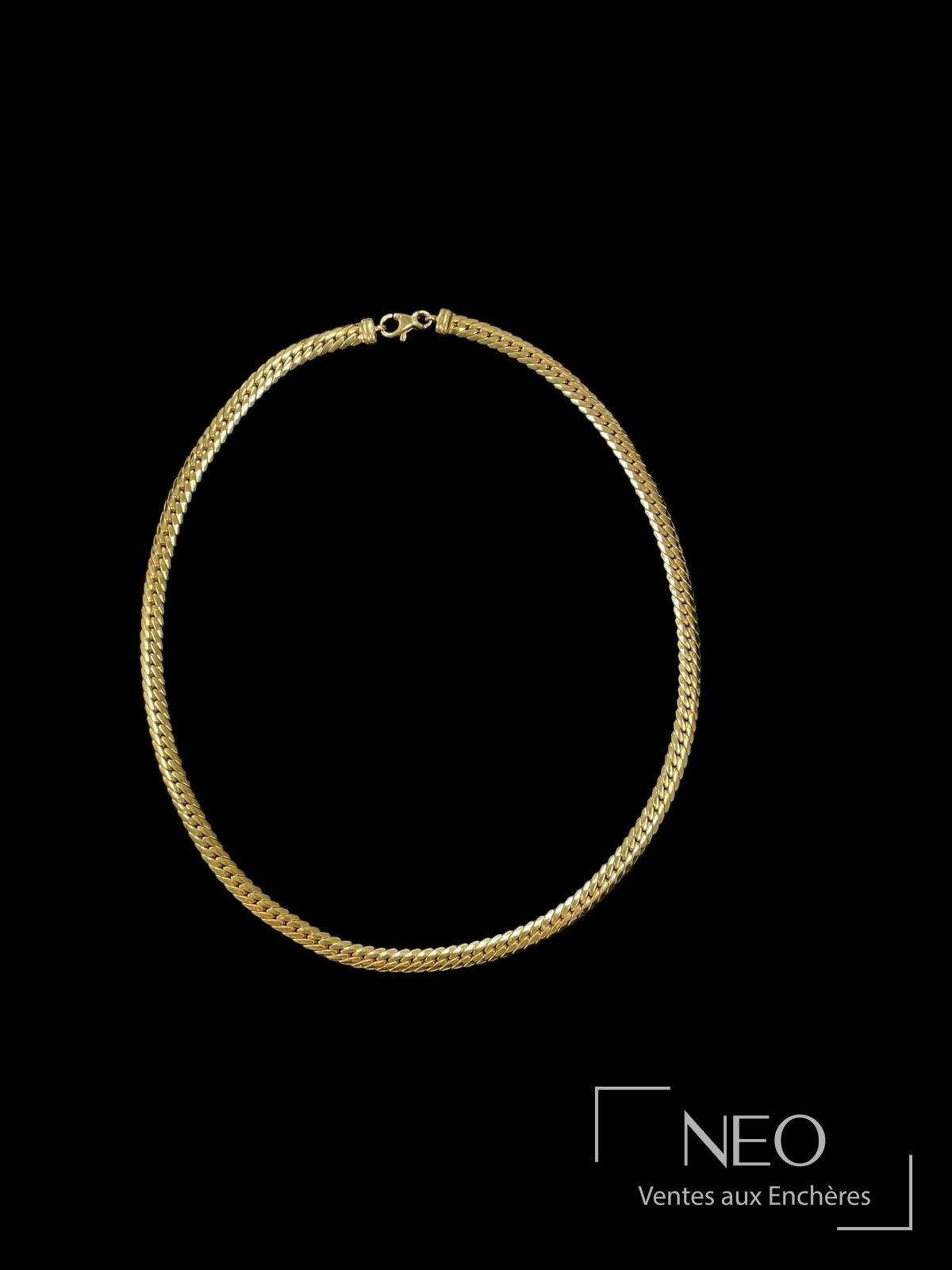 Collier en or jaune à mailles anglaises sur fond noir.