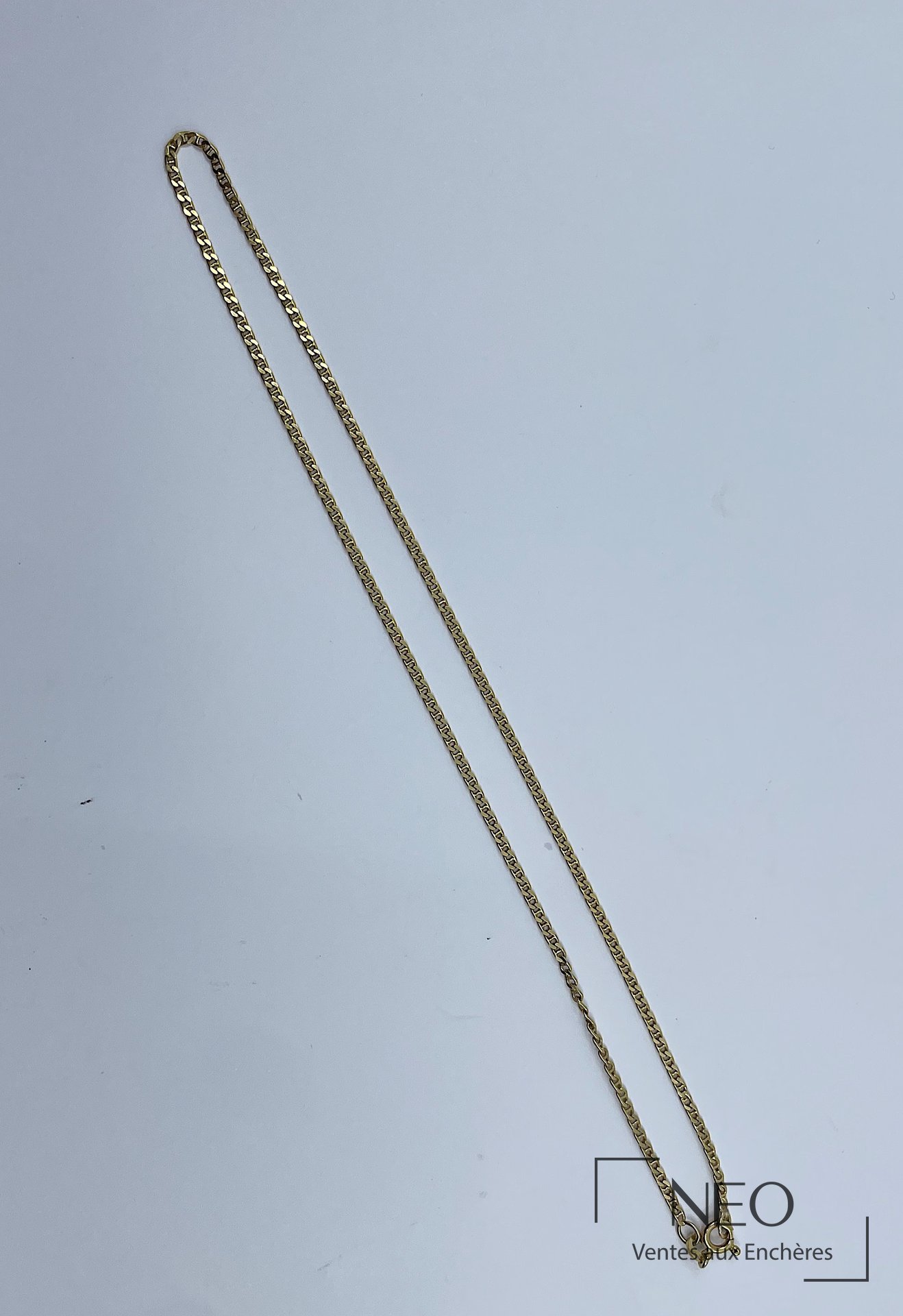 Collier en or jaune à maille souple présenté sur fond clair
