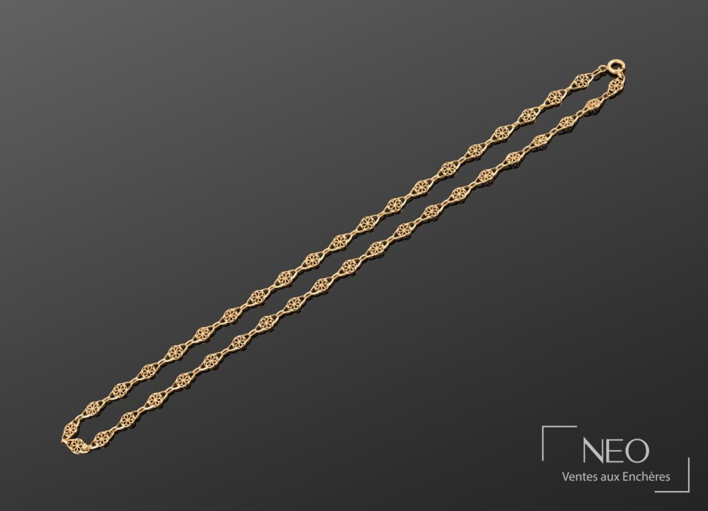 Collier en or jaune à maillons rosaces disposé en longueur sur fond sombre