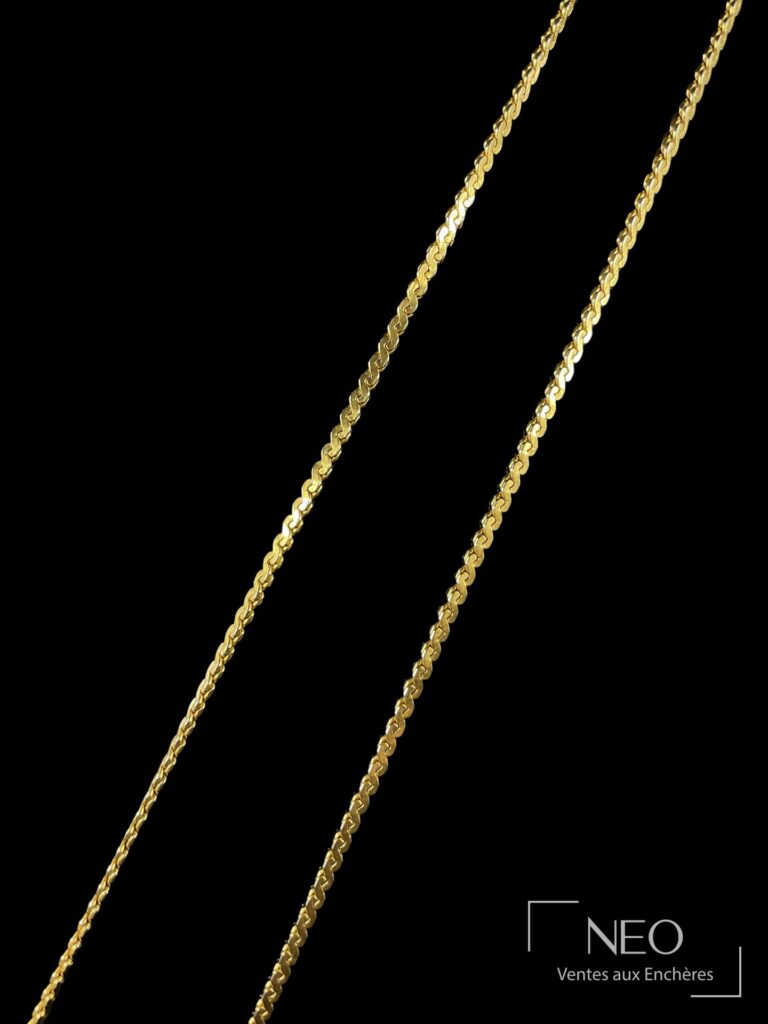Collier en métal doré à maille fantaisie présenté de face sur fond noir