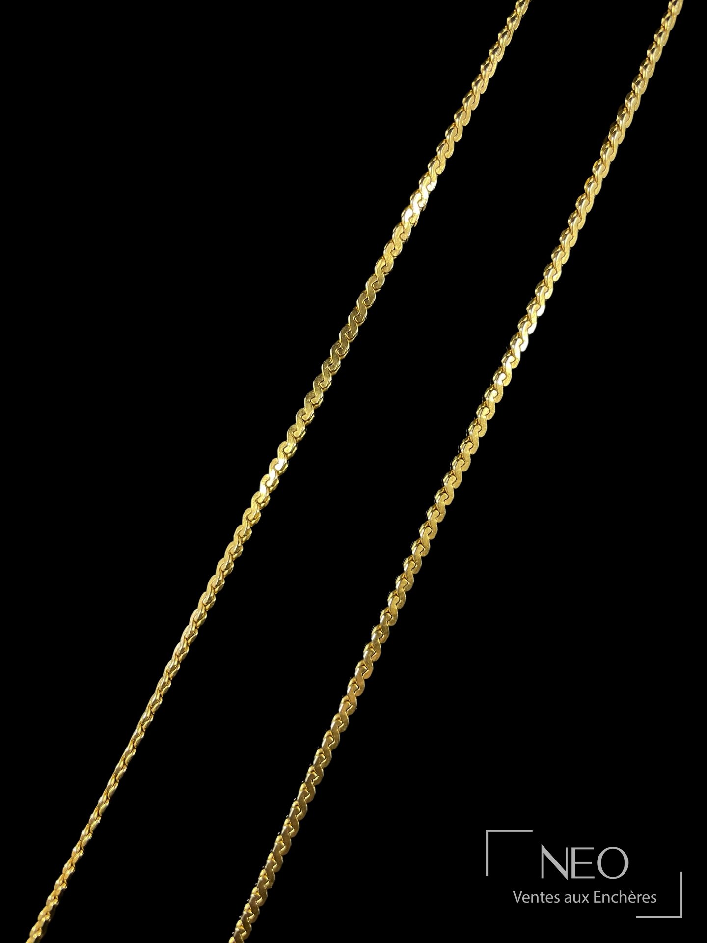 Collier en métal doré à maille fantaisie présenté de face sur fond noir