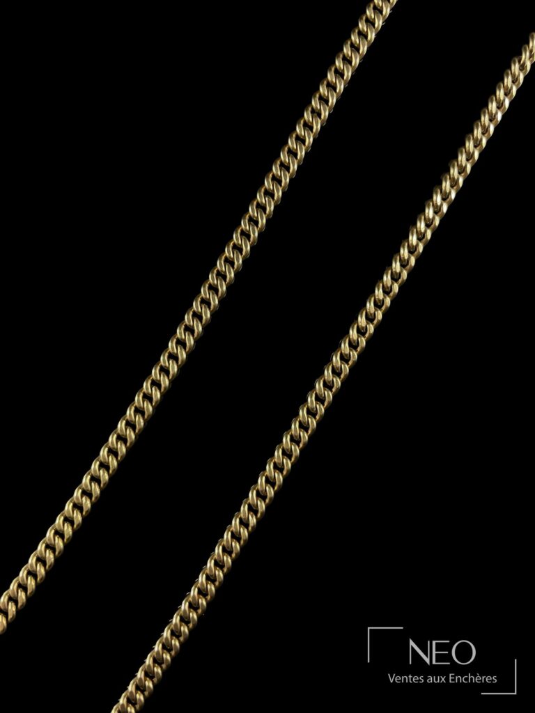 Collier en métal doré à maille gourmette présenté de face sur fond noir