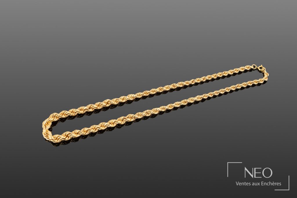 Collier en or jaune à mailles ondulées et torsadées sur fond gris