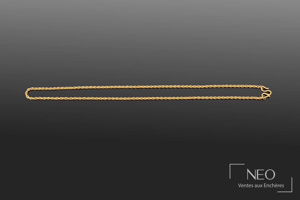 Collier en or jaune à maille torsadée présenté en entier sur fond gris.