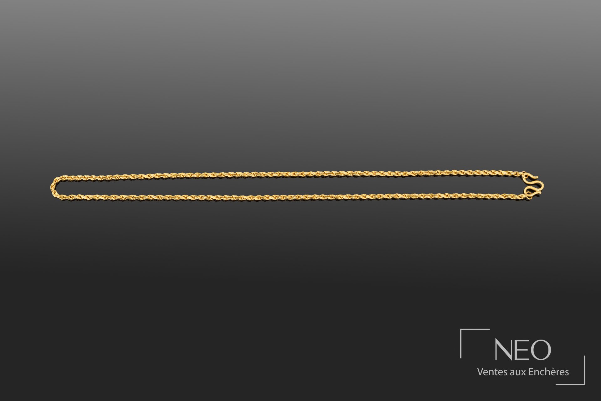 Collier en or jaune à maille torsadée présenté en entier sur fond gris.