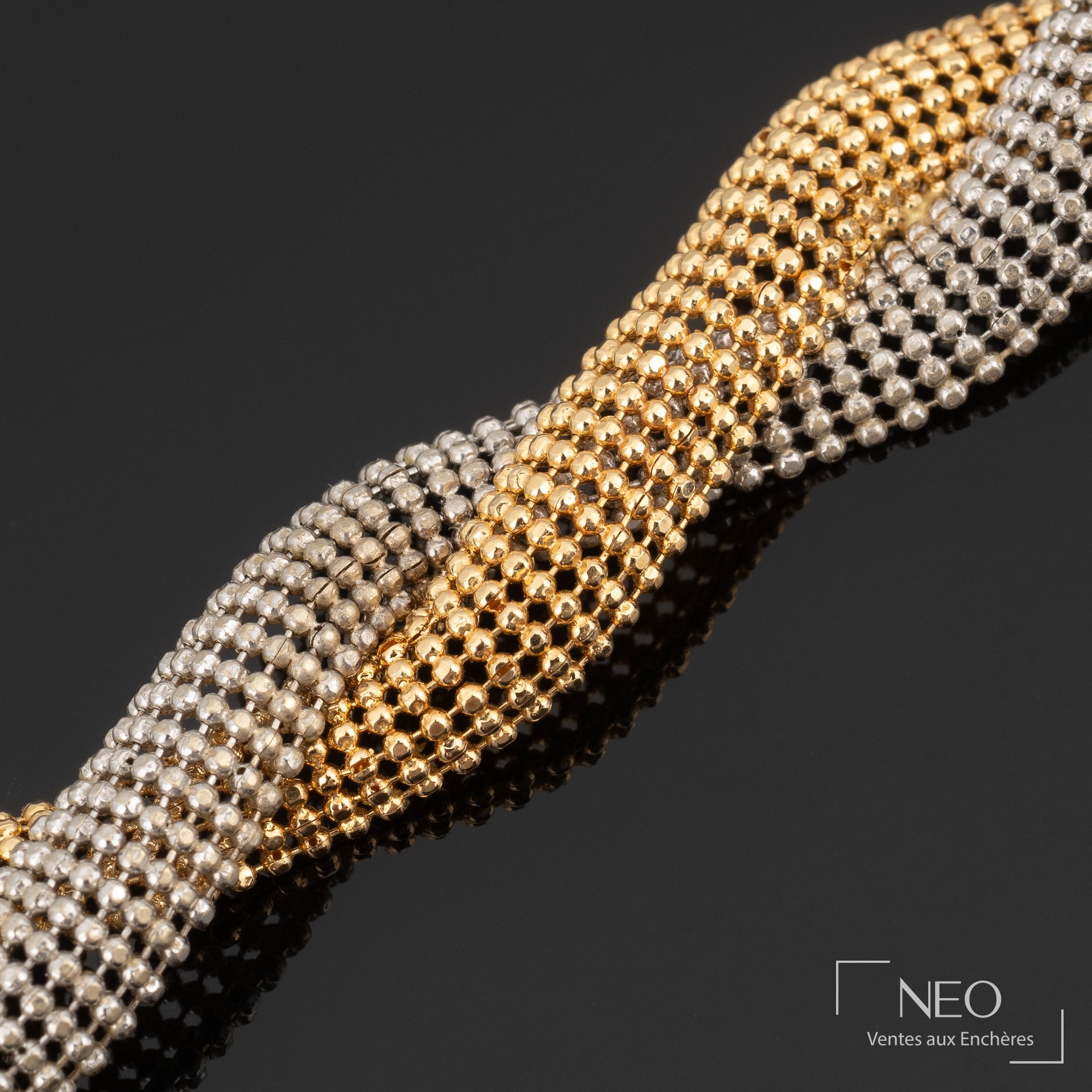 Maille résille entremêlée en or jaune et or gris sur fond noir