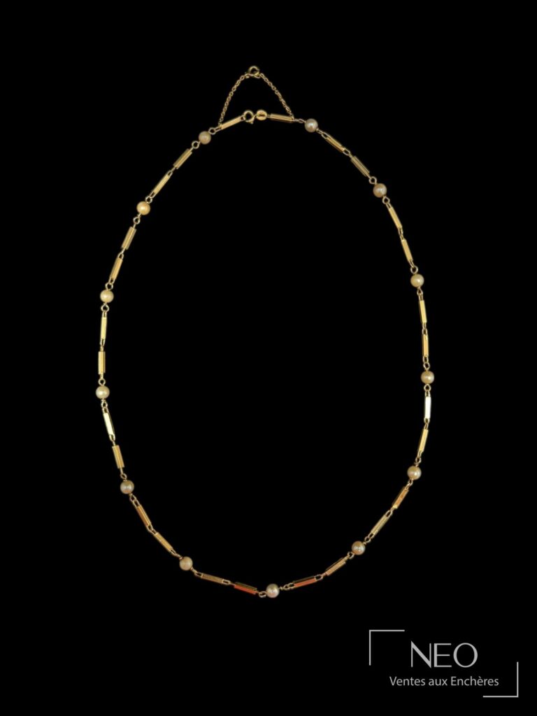 Collier en or jaune à mailles alternées et perles blanches sur fond noir