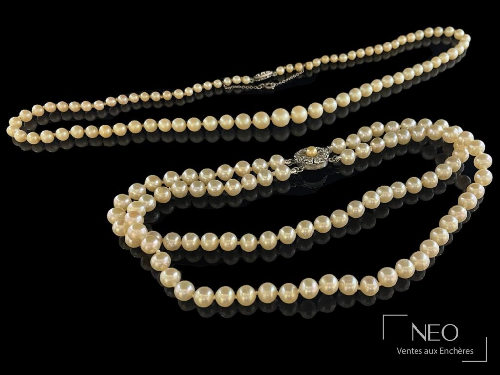 Deux colliers de perles blanches disposés sur fond noir